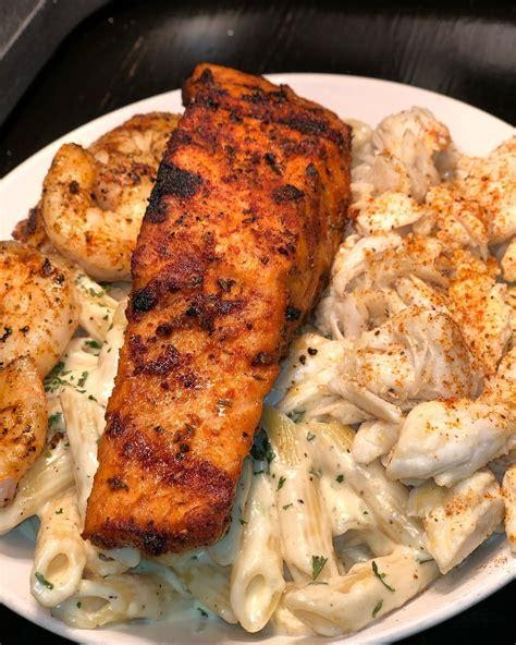 Grilled salmon and shrimp on a bed of creamy penne pasta.