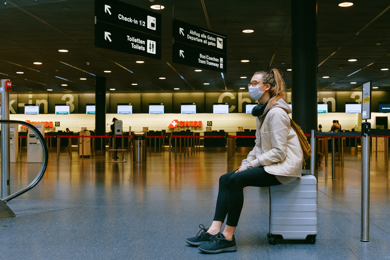 lady sitting on luggage in train station 
