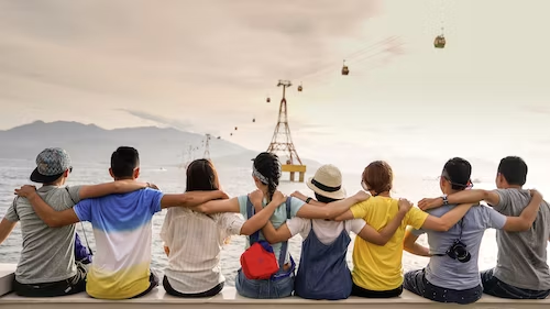 People hold each other’s shoulders while sitting on a wall and watching cable cars.People hold each other’s shoulders while sitting on a wall and watching cable cars.