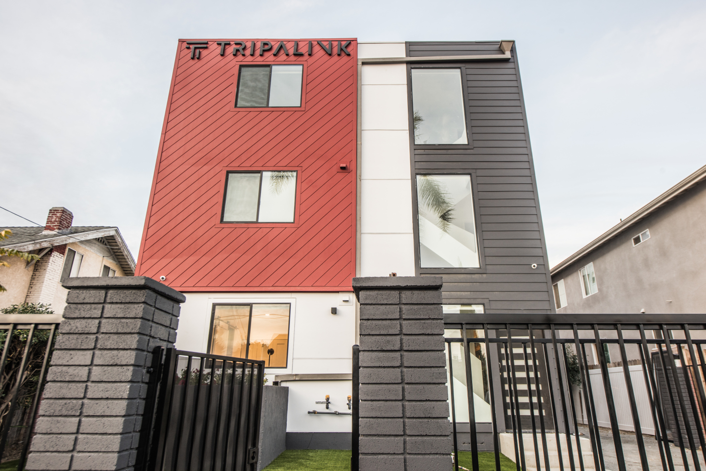 Red and grey exterior of apartment building, black gate,  Tripalink 