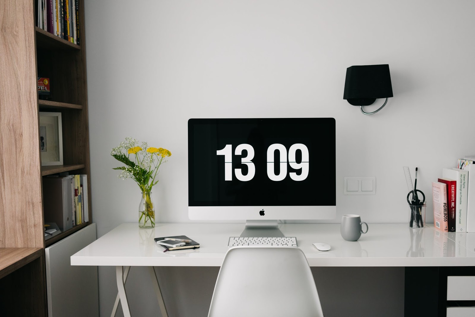 iMac with 13:09 on screensaver and computer desk