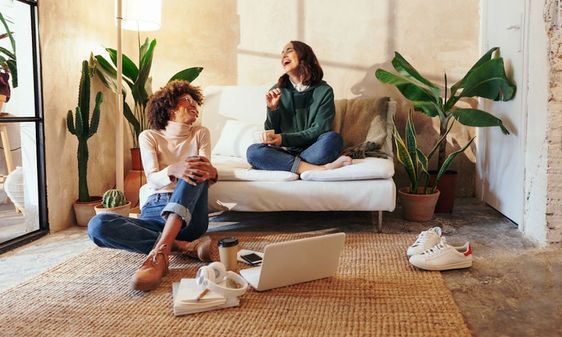 two laughing women in co-living living space, with green plants for decor 