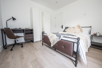 large bedroom with light brown hardwood floors and bed
