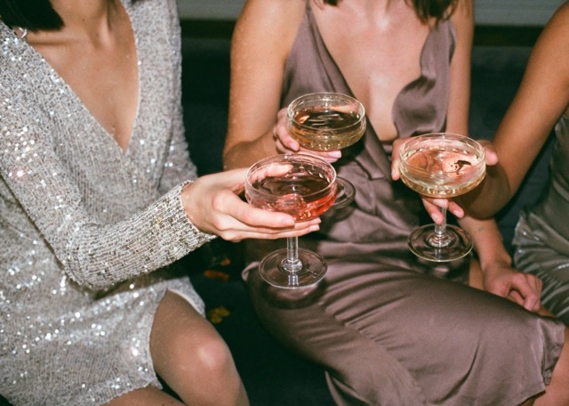 A few ladies in sparkly dresses, drinking cocktails