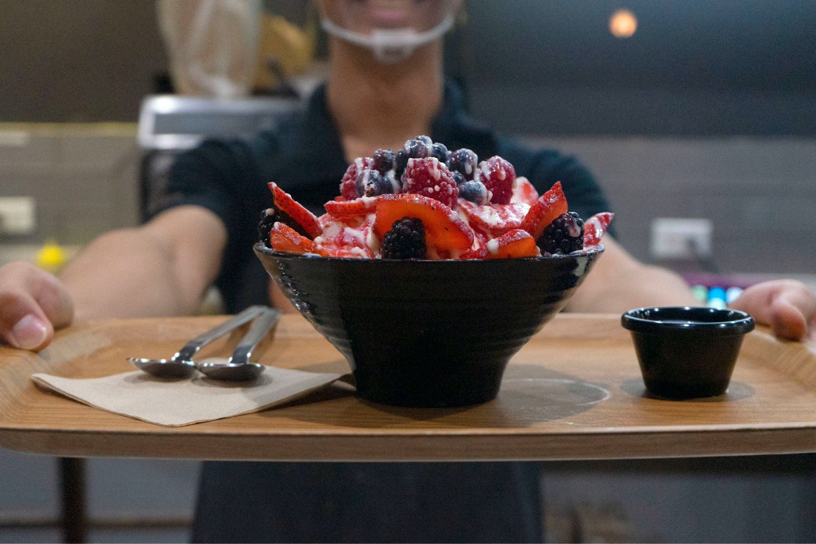 A server with a tray with cutlery, a side bowl, and a bowl of bingsu at Sul and Beans. Photo credit: Sul and Beans.