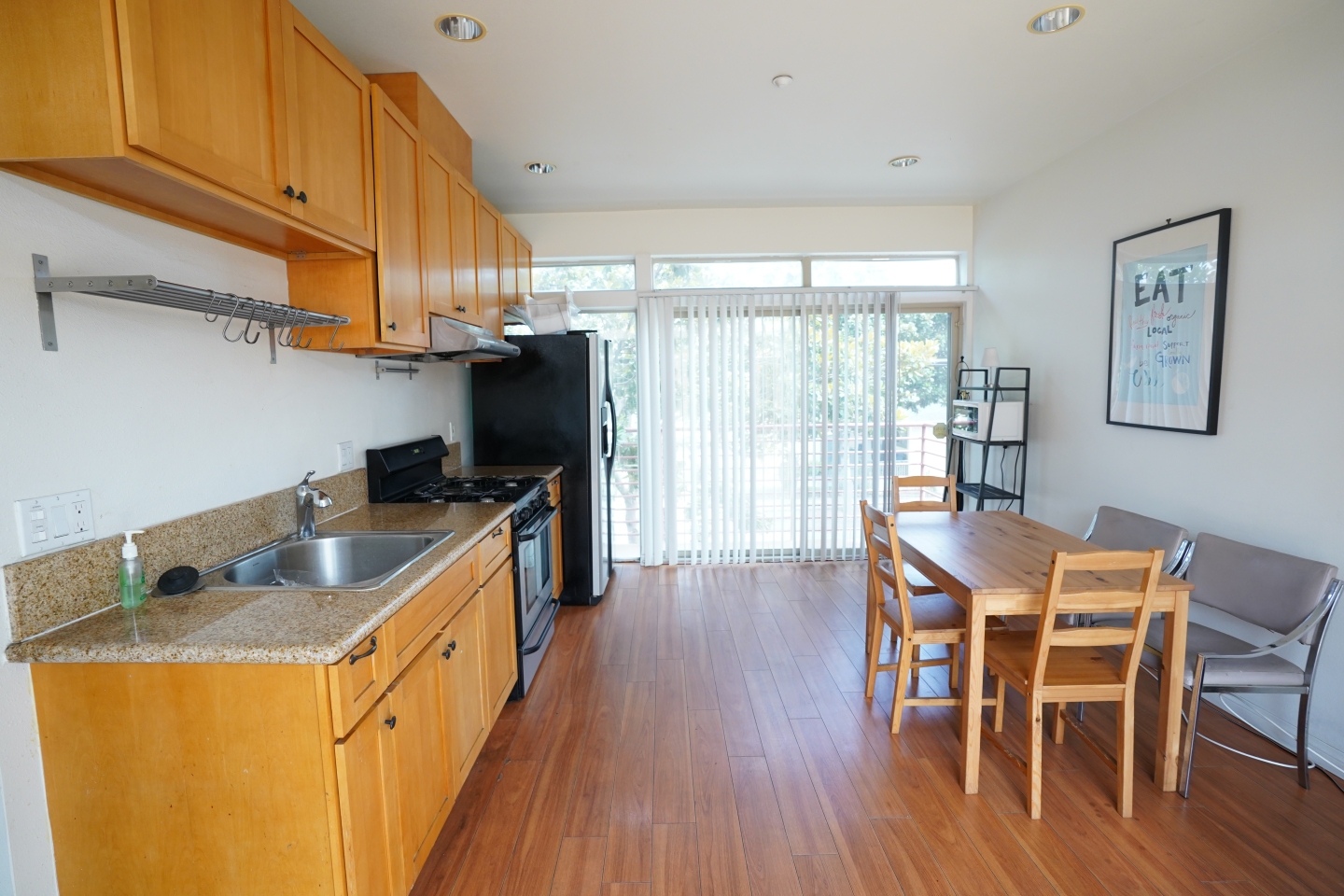 side view of kitchen, brown hardwood floors, brown cabinets and brown dining table 