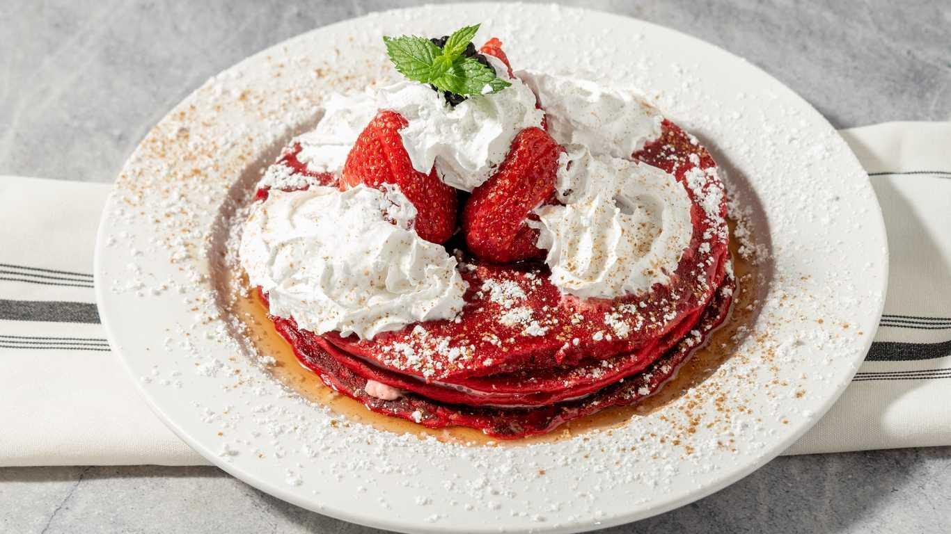 Red Velvet Pancakes topped with cream, strawberries, and mint.