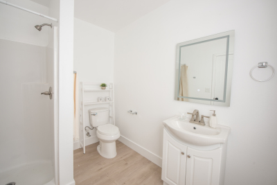 all white bathroom with light brown hardwood floors 