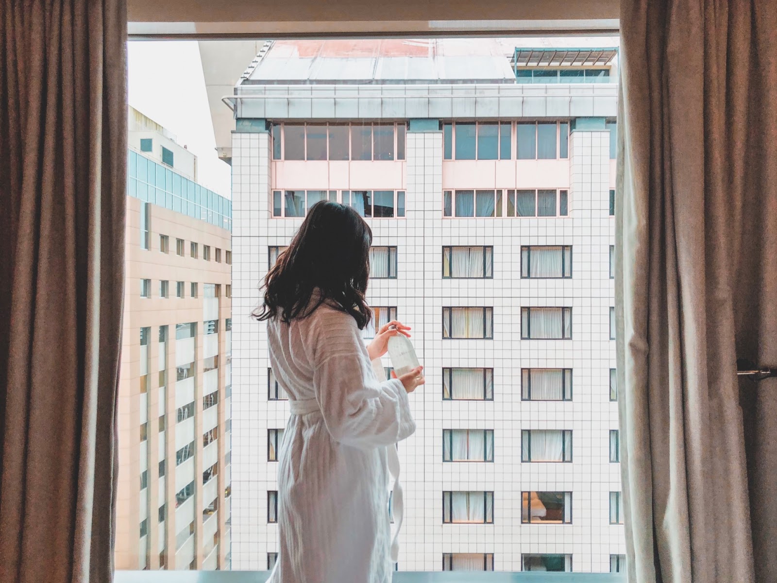 Woman in robe looking out apartment window 