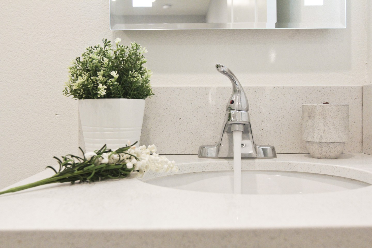 White sink with running water, green plant next to sink 