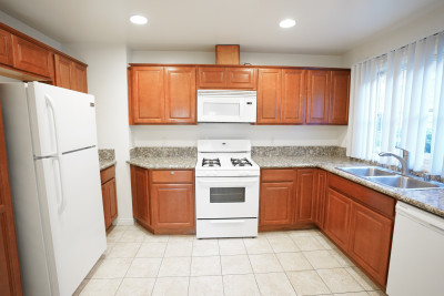 Kitchen, white tile floors, White appliances and red stained wood cabinets 