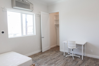 white one bedroom room, white desk with white rolling chair, Light brown hardwood floors 