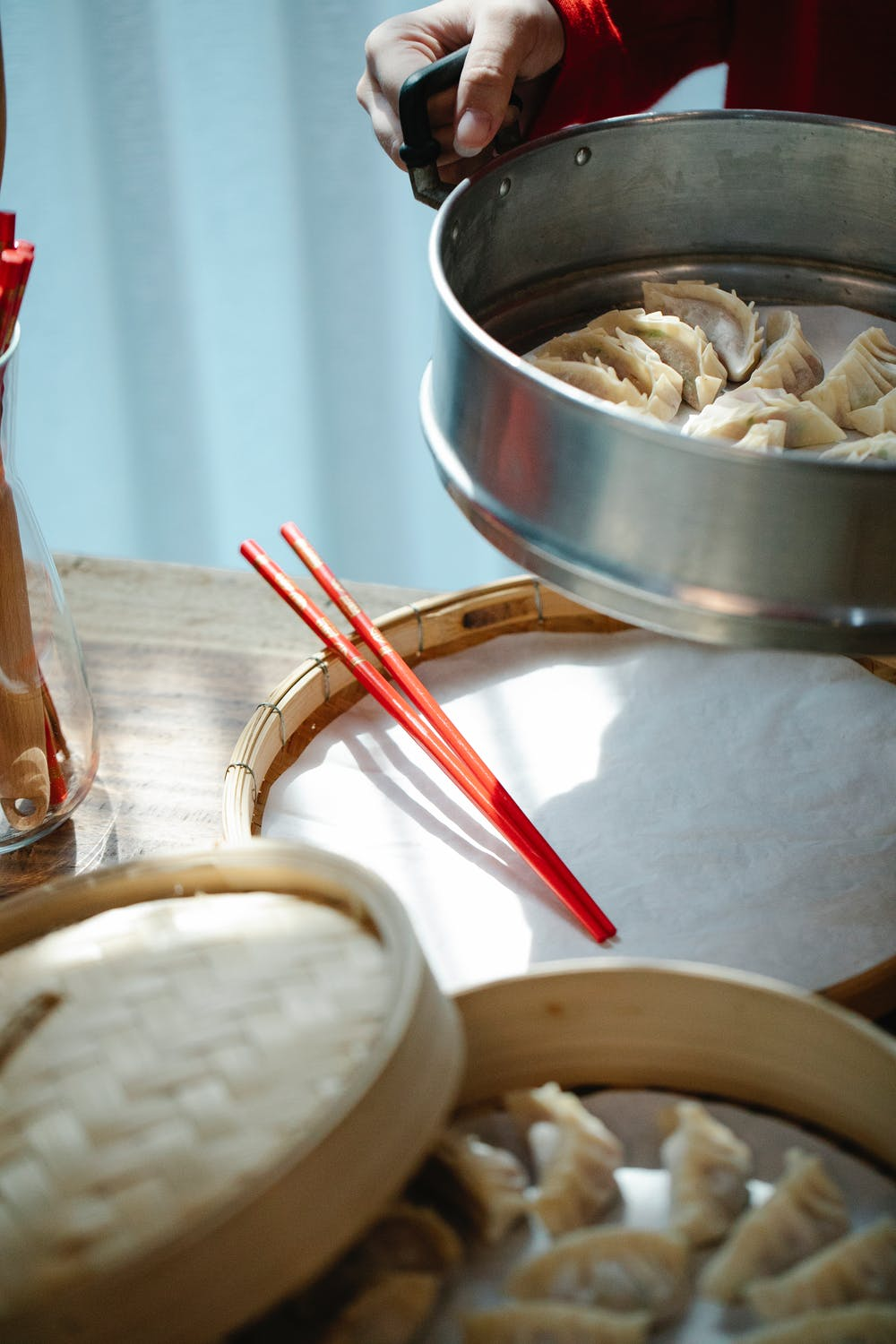 A chef carrying a pot of dumplings to prepare them for serving on a wooden platter with chopsticks.