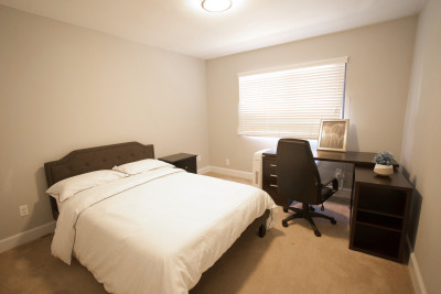 private bedroom furnished with black desk, chair and bed