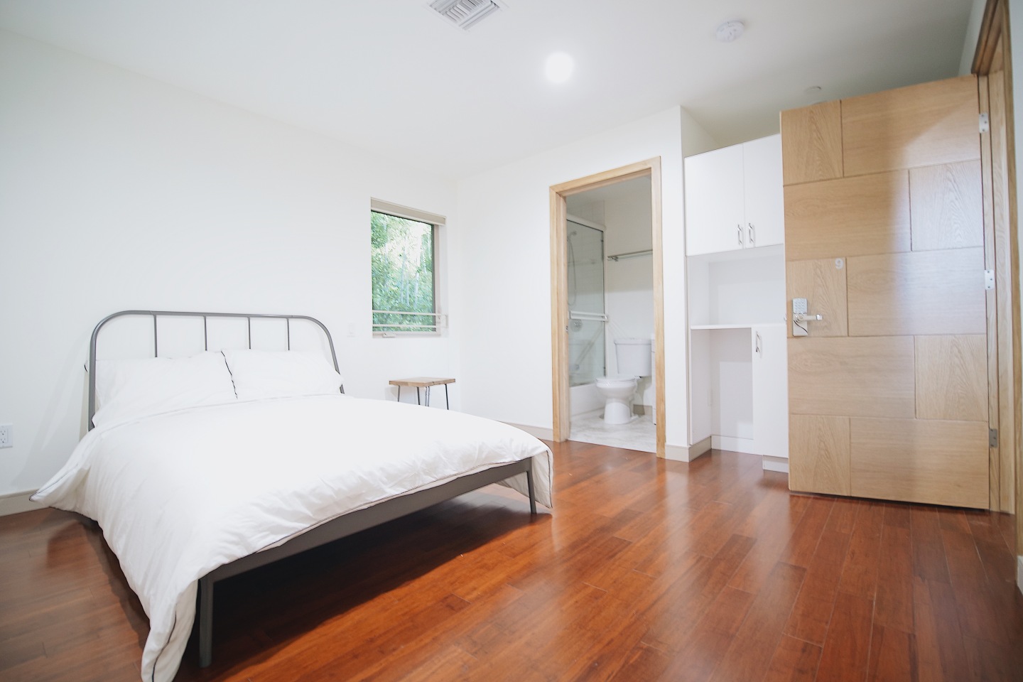 bedroom, white bed, steel bed frame, brown hardwood floor 
