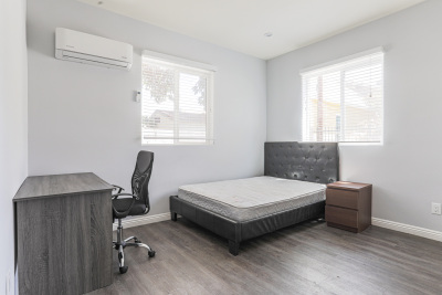 Gray wood computer desk, leather black bed frame with uncovered mattress