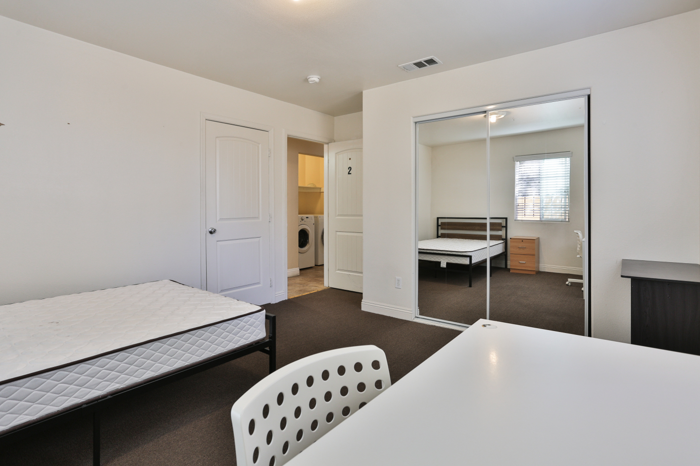bedroom view, white mattress, white desk, grey carpet 
